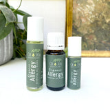 Three bottles of Oil Joy Apothecary Organic Allergy Essential Oil Blend on a white surface with a plant in the background.