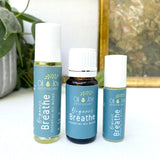 Three bottles of Oil Joy Apothecary Organic Breathe essential oil blend on a white surface with a plant in the background.