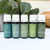 Five bottles of organic essential oils with labels on a white surface.