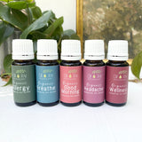 Set of essential oil bottles with labels on a white surface with greenery in the background