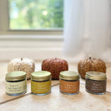 Five jars of organic tea blends on a surface with a window in the background