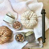 Jars of organic tea on a textured white cloth with decorative pumpkins