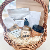 Postpartum gift basket with various items including a candle, lotion, soup, bath soak, and healing products on a light surface.