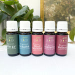 Set of essential oil bottles with labels on a white surface with greenery in the background