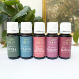 Set of essential oil bottles with labels on a white surface with greenery in the background