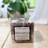 Packaged cherry pit therapy pack labeled 'thera-pitics' on a surface with a plant in the background