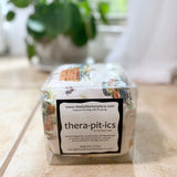 Thera-pit-ics product packaging on a table with a plant in the background