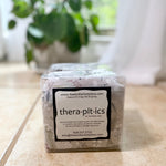 Thera-pit-ics product packaging on a surface with a plant in the background
