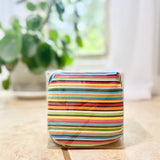 Colorful striped cherry pit therapy pack in clear packaging on a light surface with a blurred plant in the background
