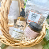 Postpartum gift basket with natural products including tallow lotion, soup mix, essential oil candle, herbal balm and sitz bath.